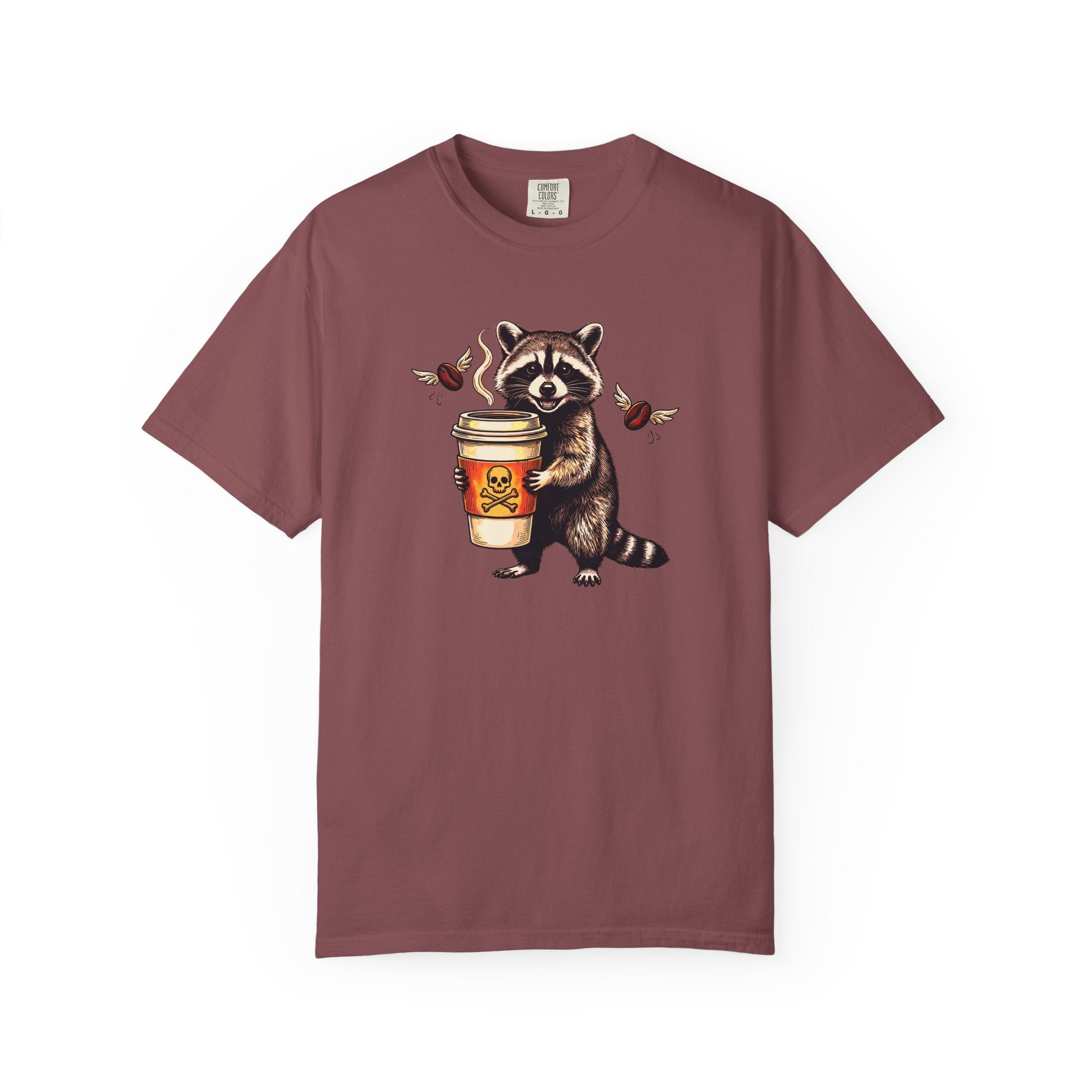 A maroon Comfort Colors 1717 unisex t-shirt featuring a graphic of a raccoon holding a coffee cup.
