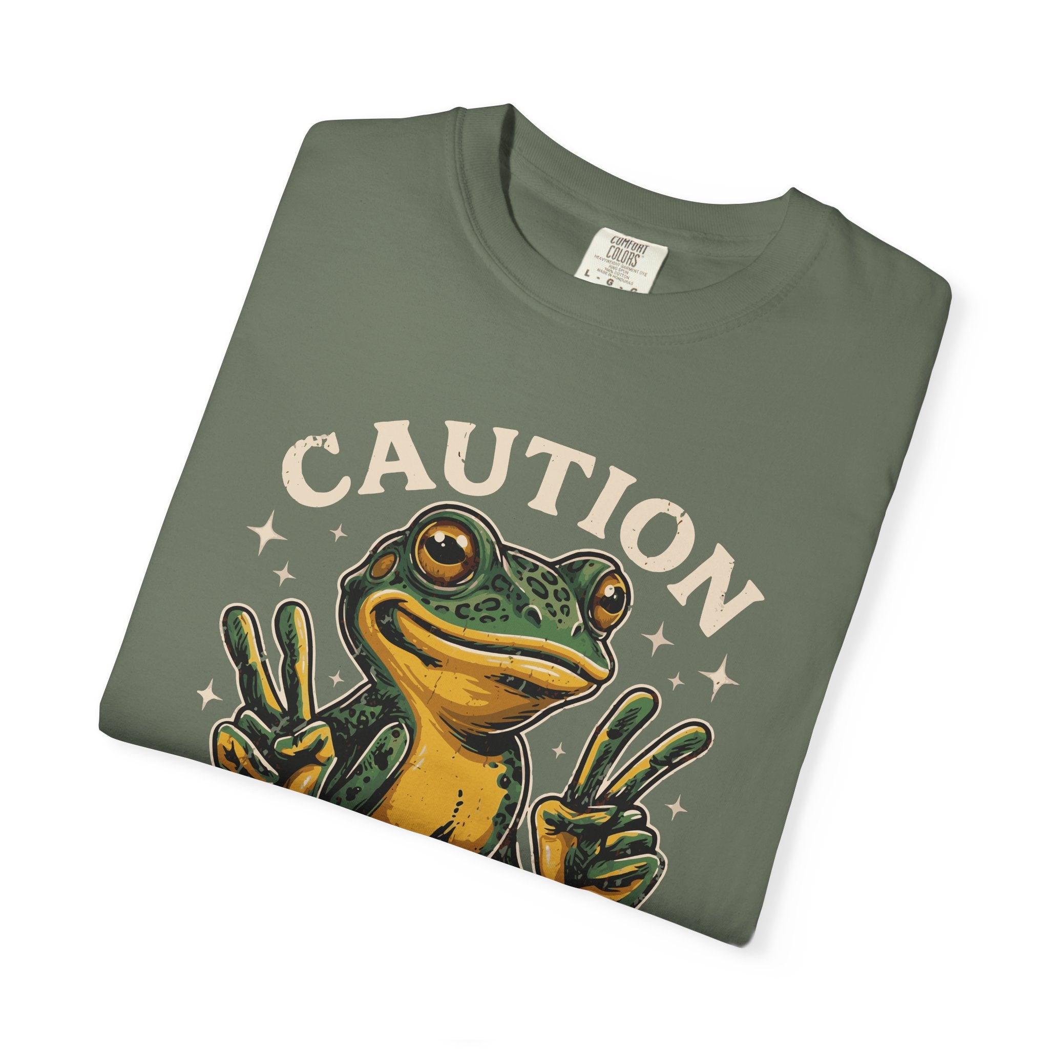 Olive green t-shirt featuring a graphic of a frog making peace signs with the text CAUTION.