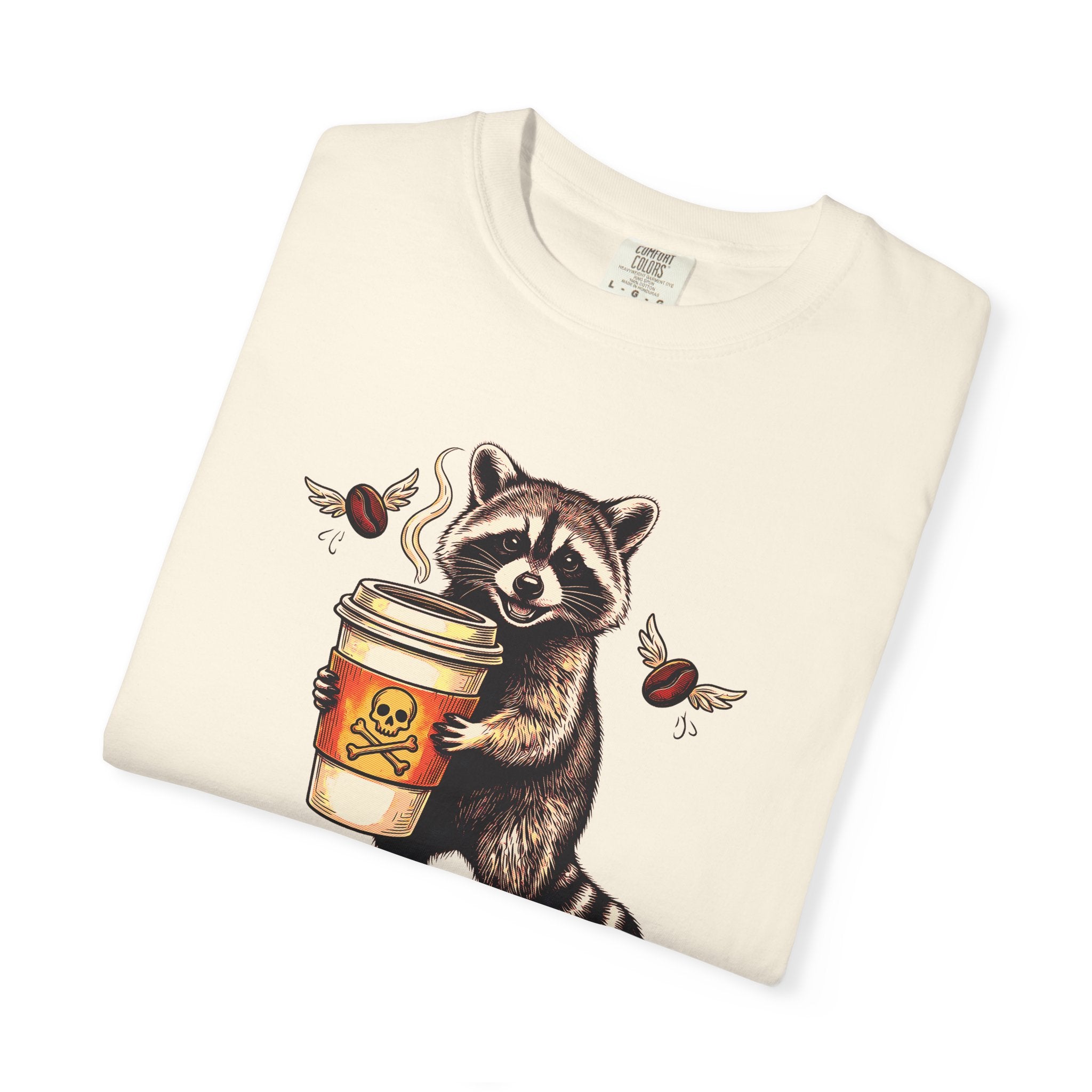 Cream-colored Comfort Colors unisex t-shirt featuring a raccoon holding a coffee cup with a skull.