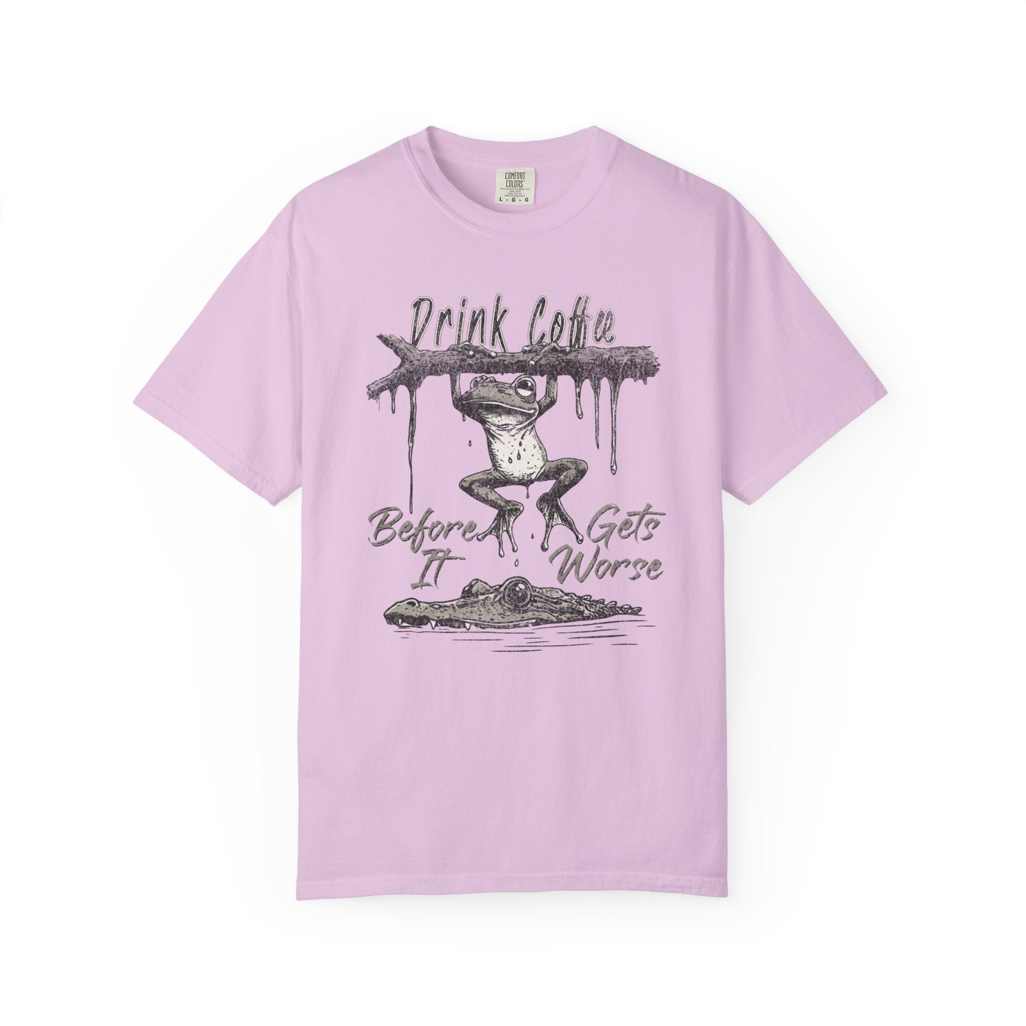 Light pink unisex t-shirt featuring a graphic of a frog hanging from a branch above an alligator.