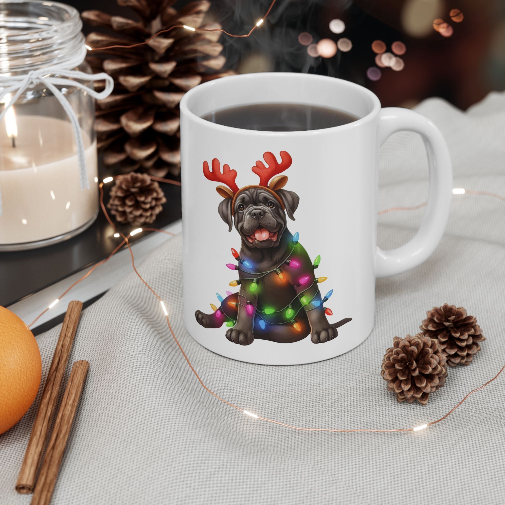 A white ceramic mug with a Cane Corso puppy wearing reindeer antlers and Christmas lights.