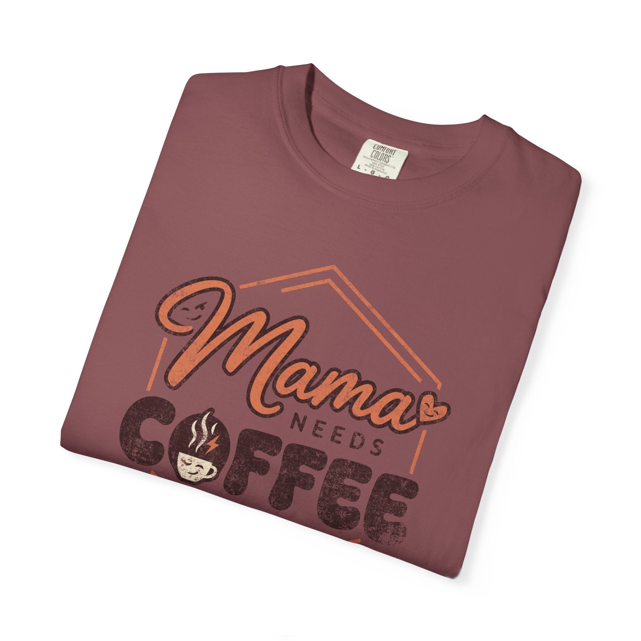 A folded vintage-wash maroon unisex t-shirt with a distressed Mama Needs Coffee graphic print.