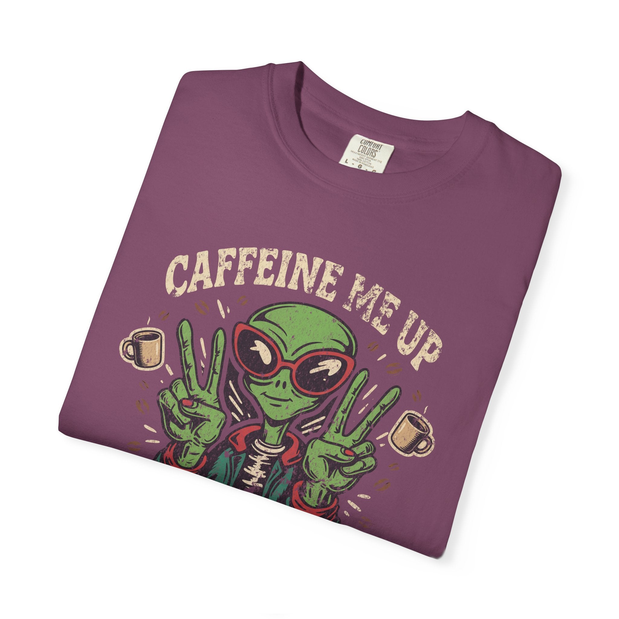 A folded purple unisex cotton t-shirt featuring a distressed graphic of an alien making peace signs.