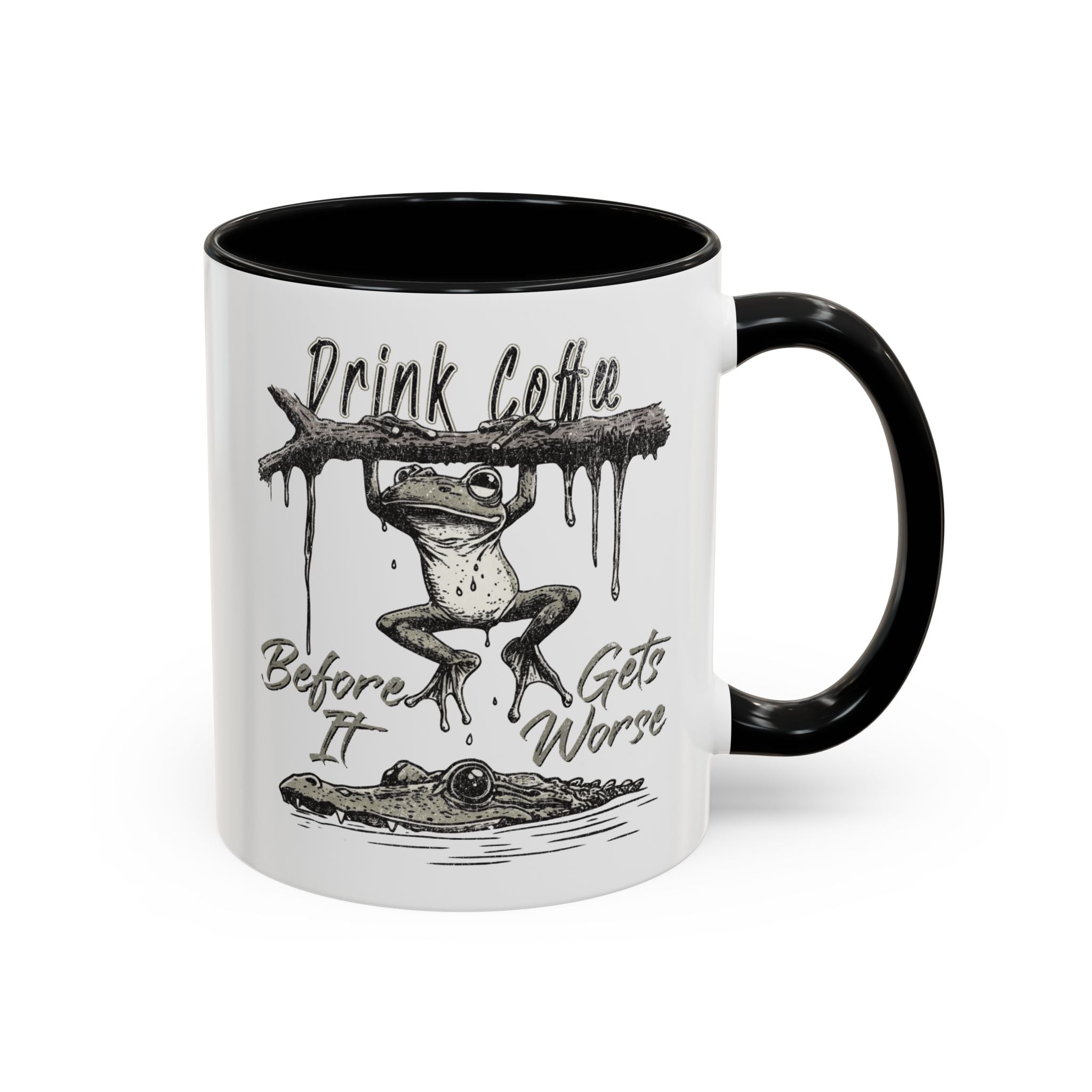 White ceramic mug with a black handle and rim, featuring a frog hanging over a crocodile.