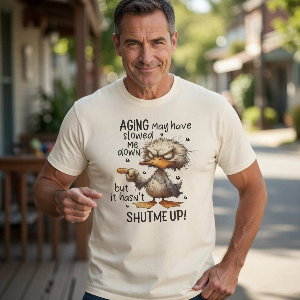 A man wears a cream-colored t-shirt featuring a grumpy duck illustration and humorous text.