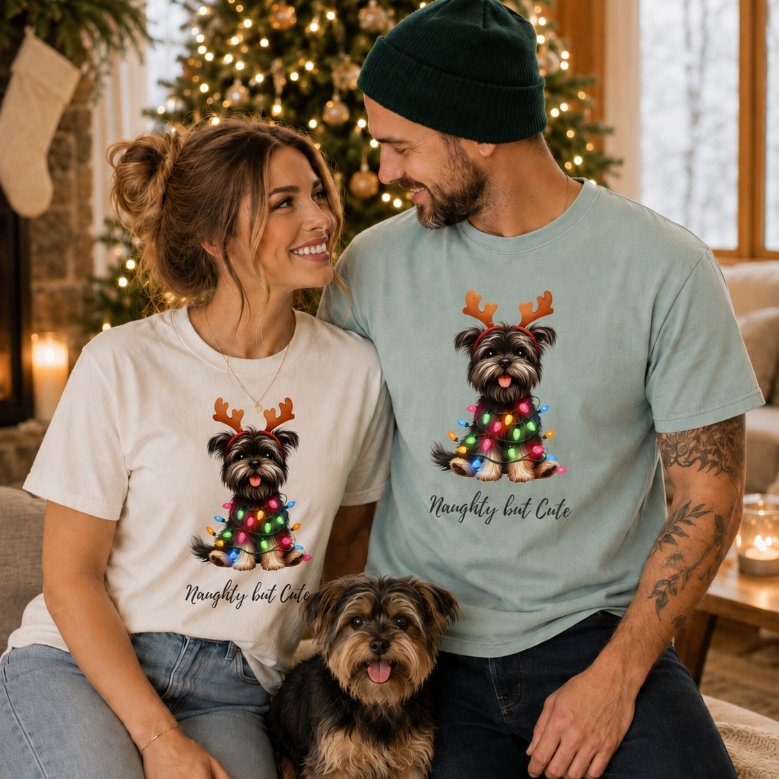 A man and woman wearing matching Yorkie Christmas graphic t-shirts with a Yorkie dog sitting nearby.
