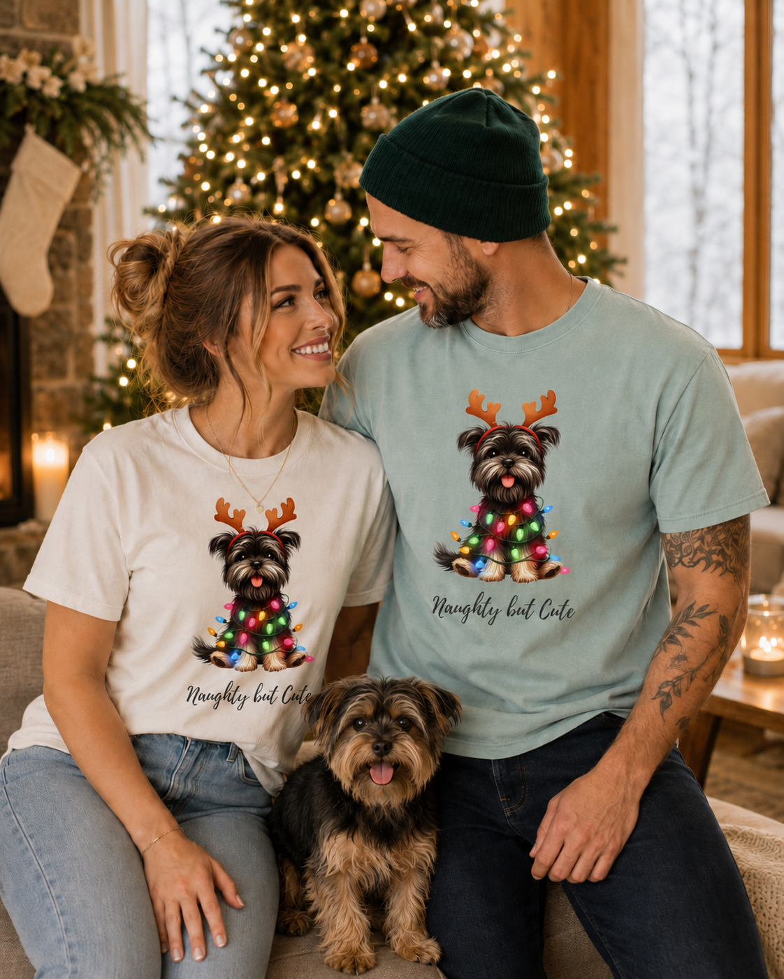 A man and woman wearing matching Yorkie Christmas graphic t-shirts with a Yorkie dog sitting nearby.