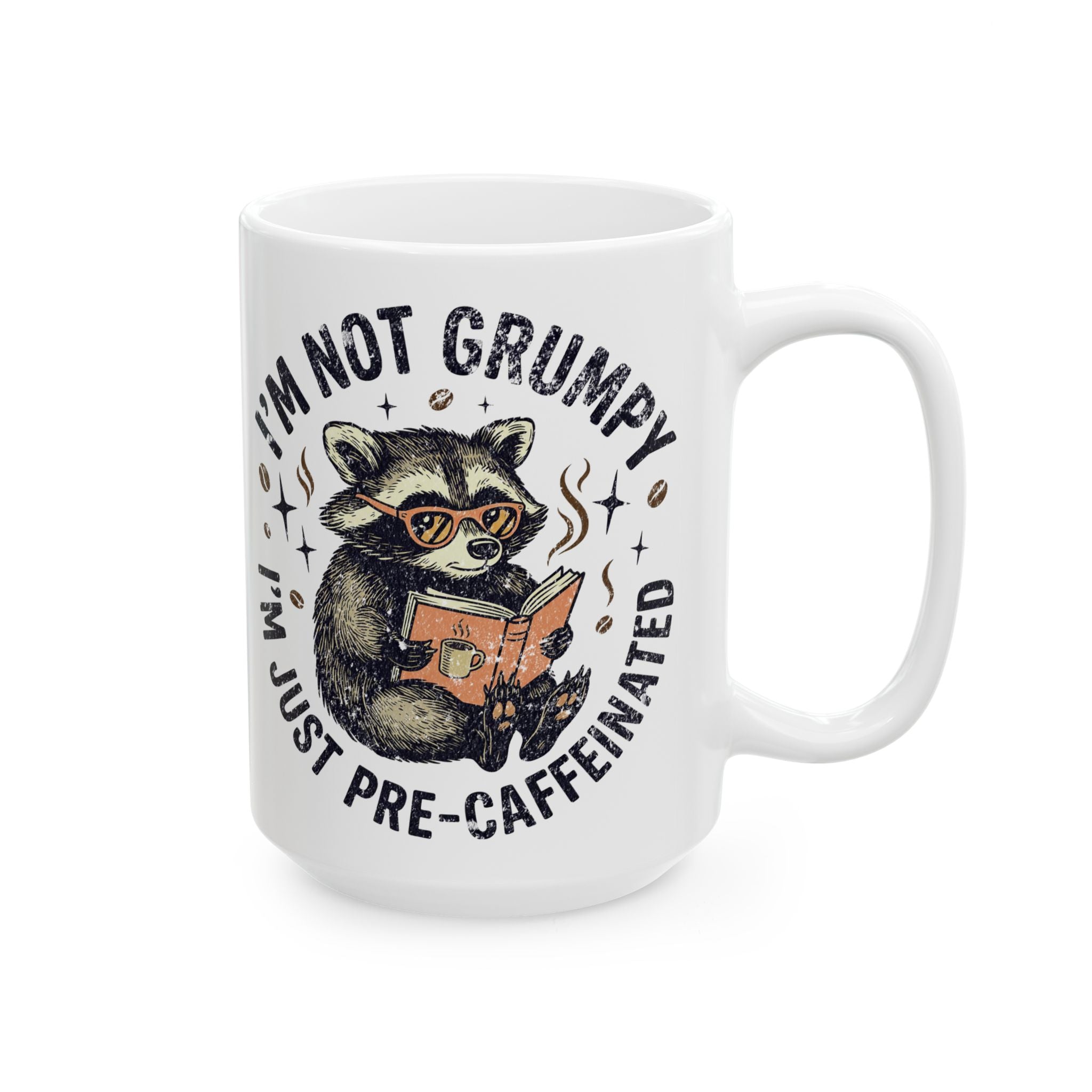 White ceramic coffee mug featuring a raccoon wearing glasses and reading a book.