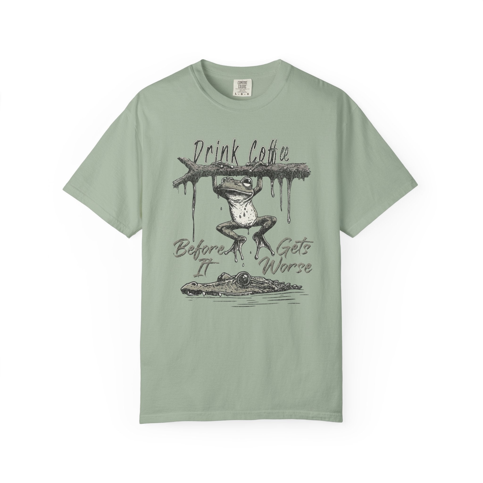 Sage green unisex t-shirt with a graphic of a frog hanging from a branch above an alligator.