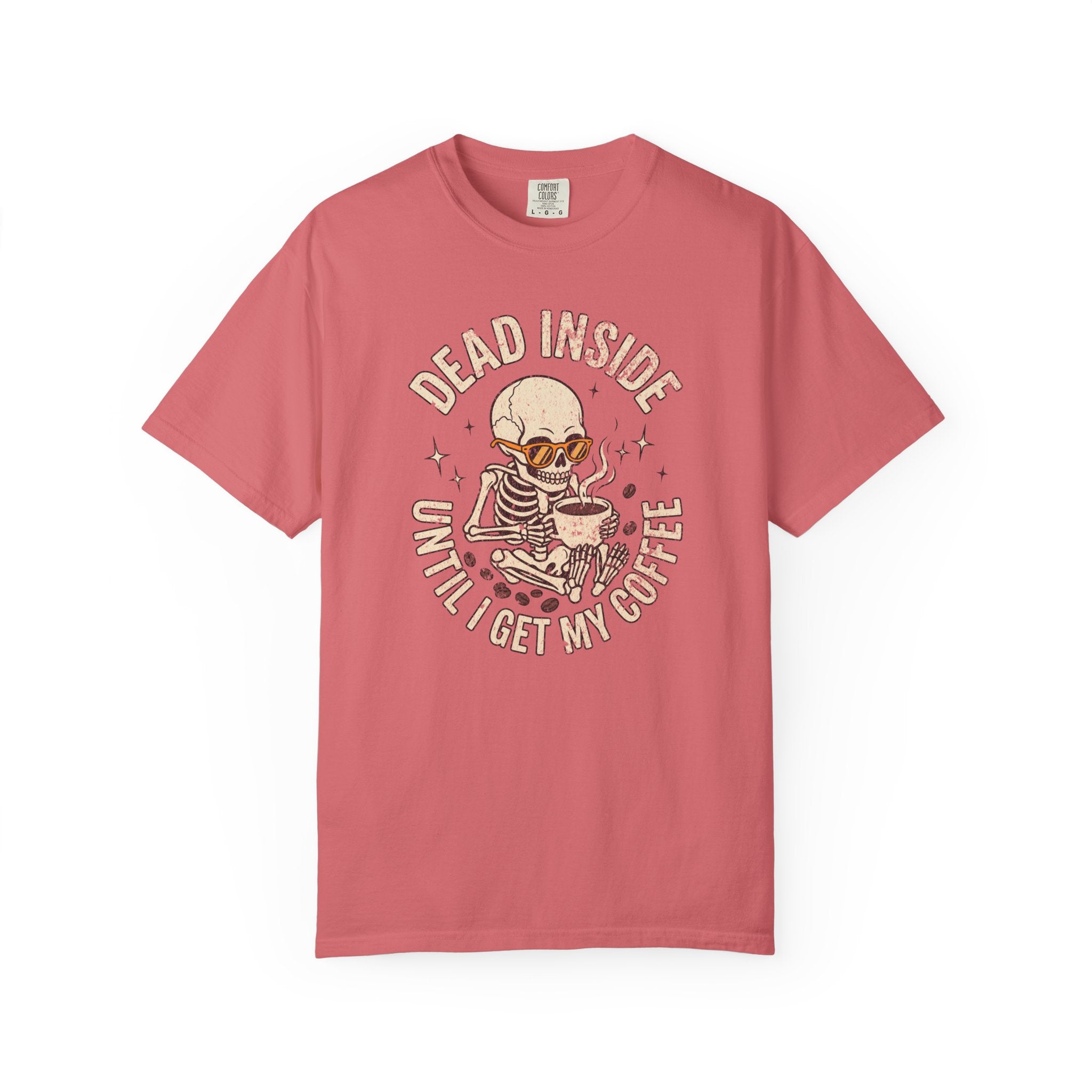 A coral-colored t-shirt featuring a skeleton wearing sunglasses and holding a coffee mug.