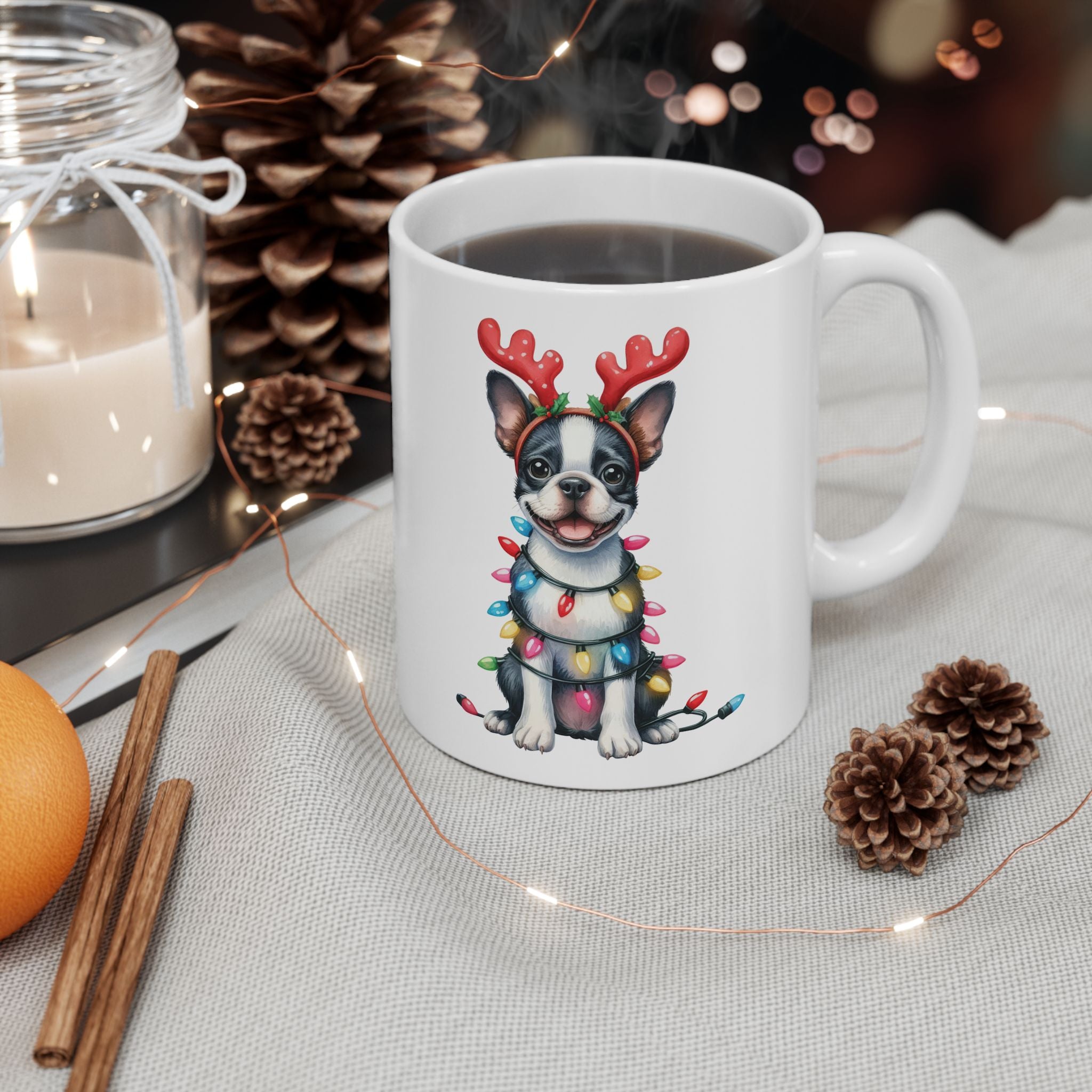 A white ceramic mug with a Boston Terrier wearing reindeer antlers and Christmas lights.