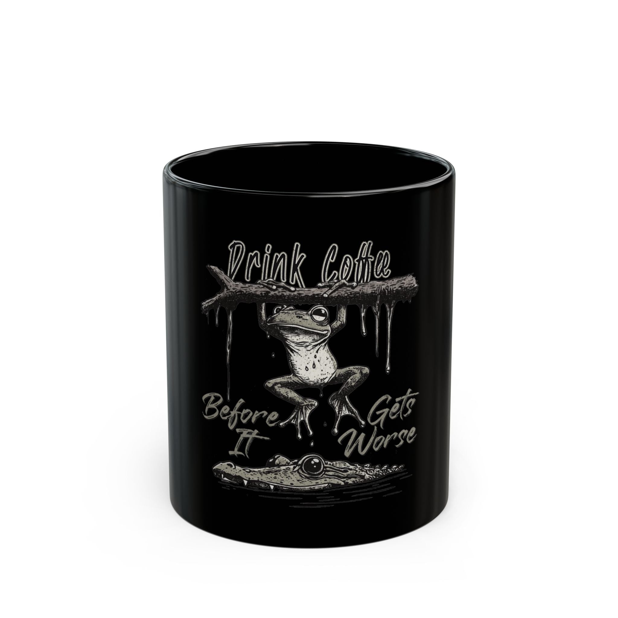 Black ceramic mug featuring a frog hanging from a branch above an alligator with text.