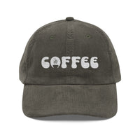 A dark grey corduroy dad hat with the word COFFEE embroidered in white on the front.