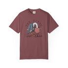 A maroon unisex t-shirt featuring a graphic of a duck with its head in a coffee mug.