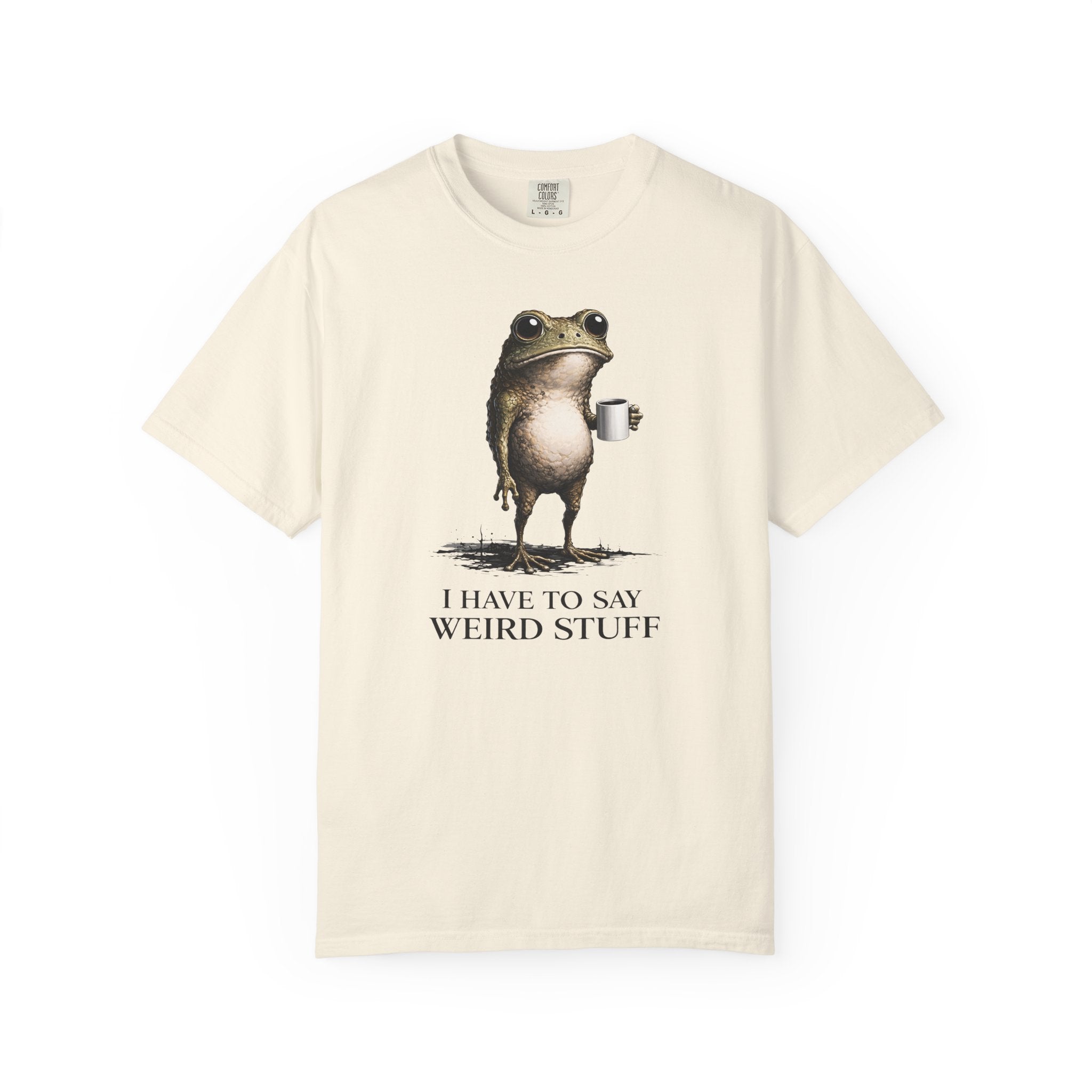 A cream-colored cotton t-shirt featuring a graphic of a frog holding a coffee mug with text below.