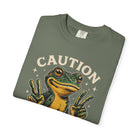Olive green t-shirt featuring a graphic of a frog making peace signs with the text CAUTION.