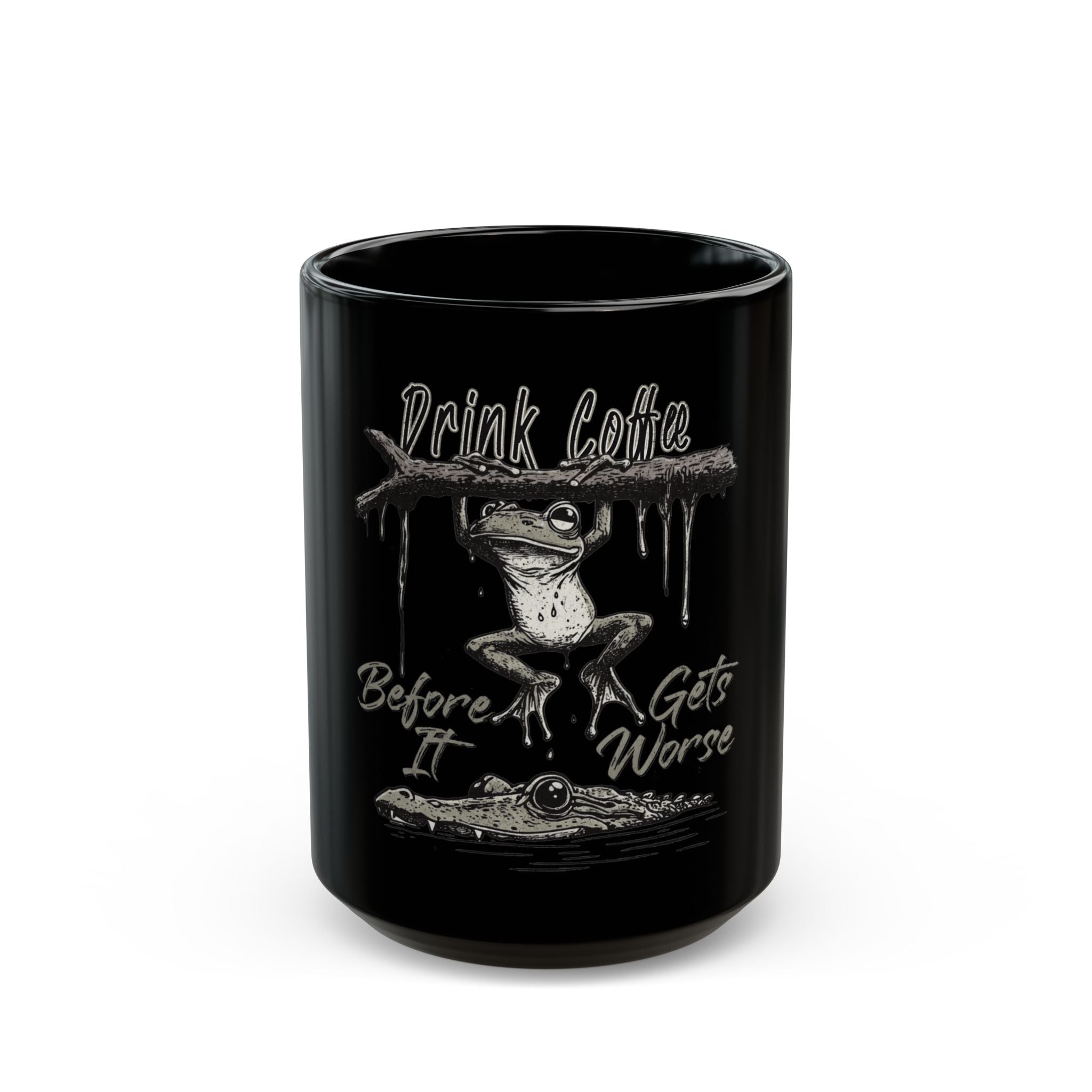 Black ceramic mug featuring a frog hanging from a branch above a crocodile with coffee text.