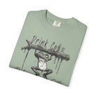 Sage green unisex t-shirt featuring a graphic of a frog hanging from a branch with Drink Coffee text.