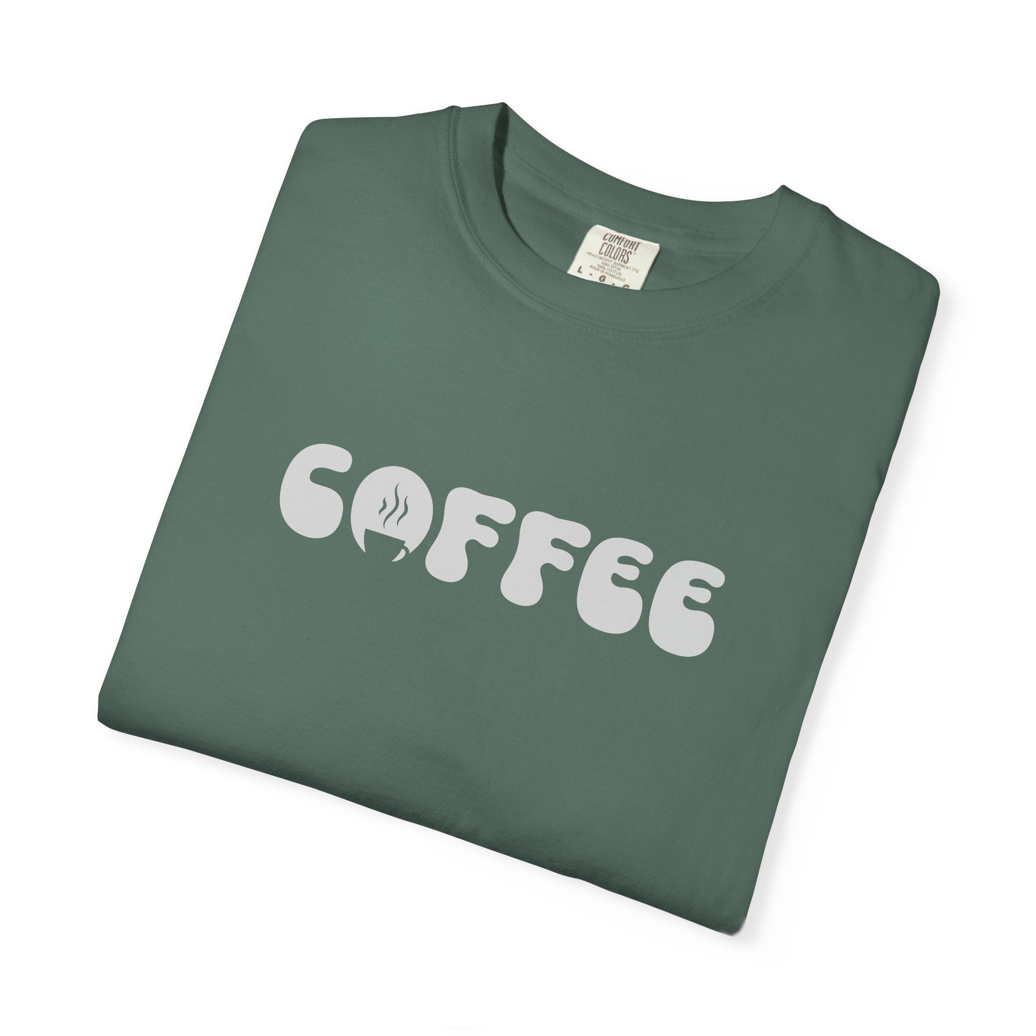 A folded sage green cotton t-shirt featuring the word COFFEE in a white retro bubble font.