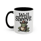 White ceramic mug with a black handle featuring a cowboy frog holding a coffee cup.