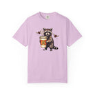 Light purple Comfort Colors unisex t-shirt featuring a raccoon holding a coffee cup with a skull.