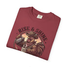 Red graphic t-shirt featuring a cowboy rooster pouring coffee with the text Rise & Shine.