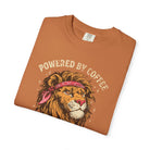 Folded orange t-shirt featuring a graphic of a lion wearing a bandana with Powered by Coffee text.