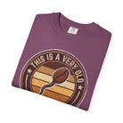 A folded purple t-shirt with a vintage-style graphic of a coffee bean and the text This Is A Very Old