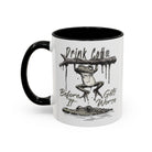 White ceramic mug with a black handle and rim featuring a frog hanging over a crocodile illustration.
