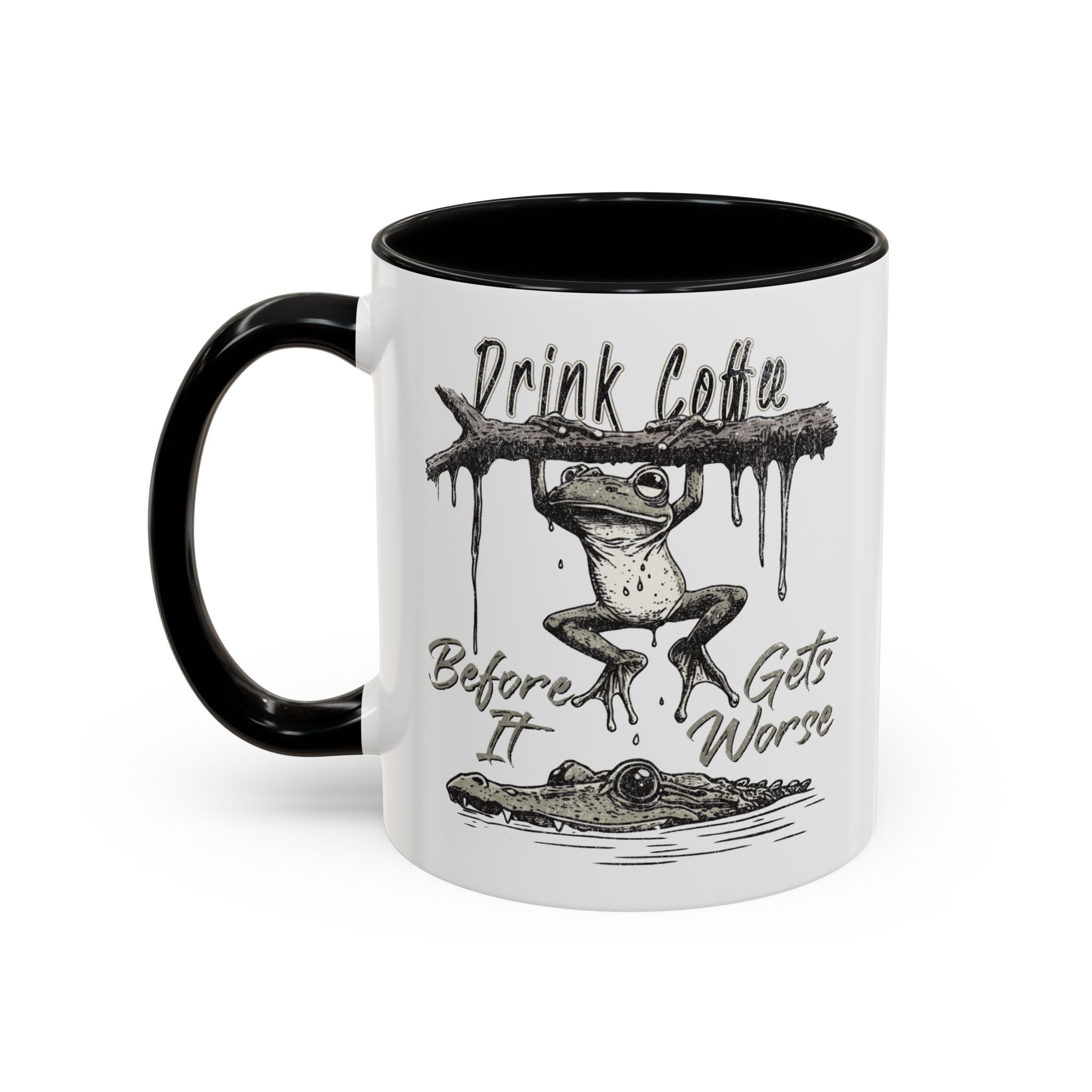 White ceramic mug with a black handle and rim featuring a frog hanging over a crocodile illustration.