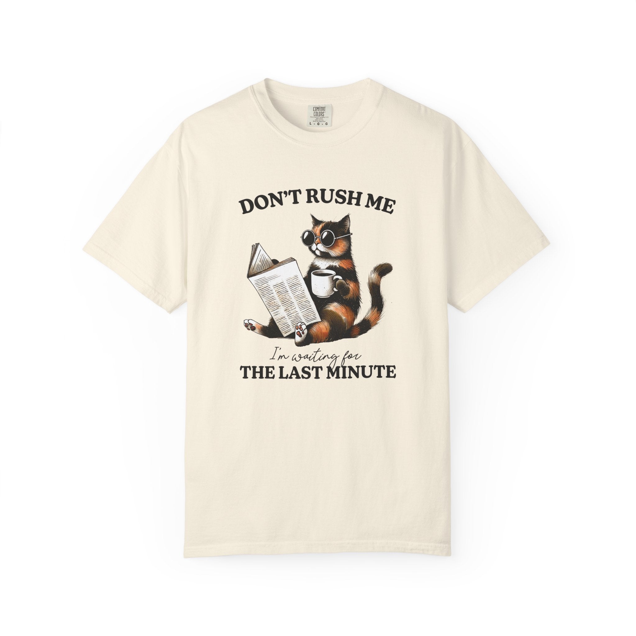 A cream-colored cotton t-shirt featuring a graphic of a cat wearing sunglasses, reading, and drinking.