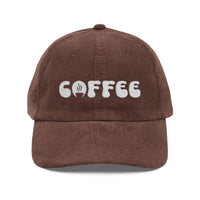 A brown corduroy dad hat with the word coffee embroidered in white on the front.