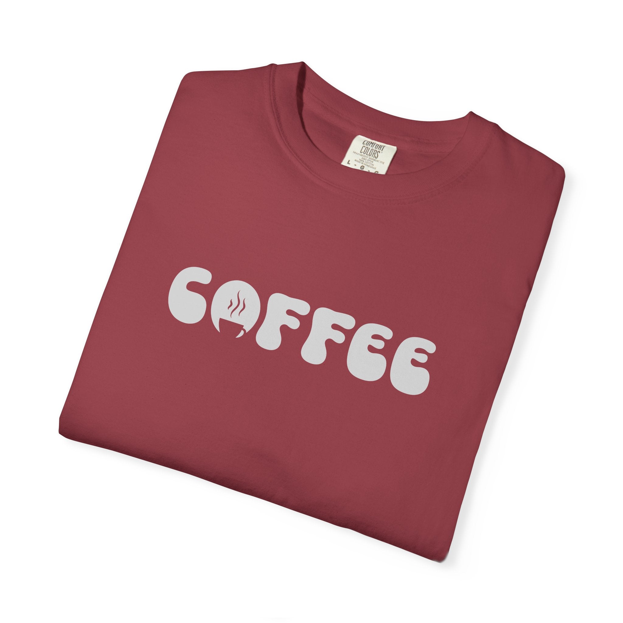 A folded maroon short-sleeve t-shirt featuring the word COFFEE in a white retro bubble font.