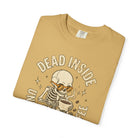 Tan t-shirt with a distressed graphic of a skeleton wearing sunglasses and holding a coffee mug.