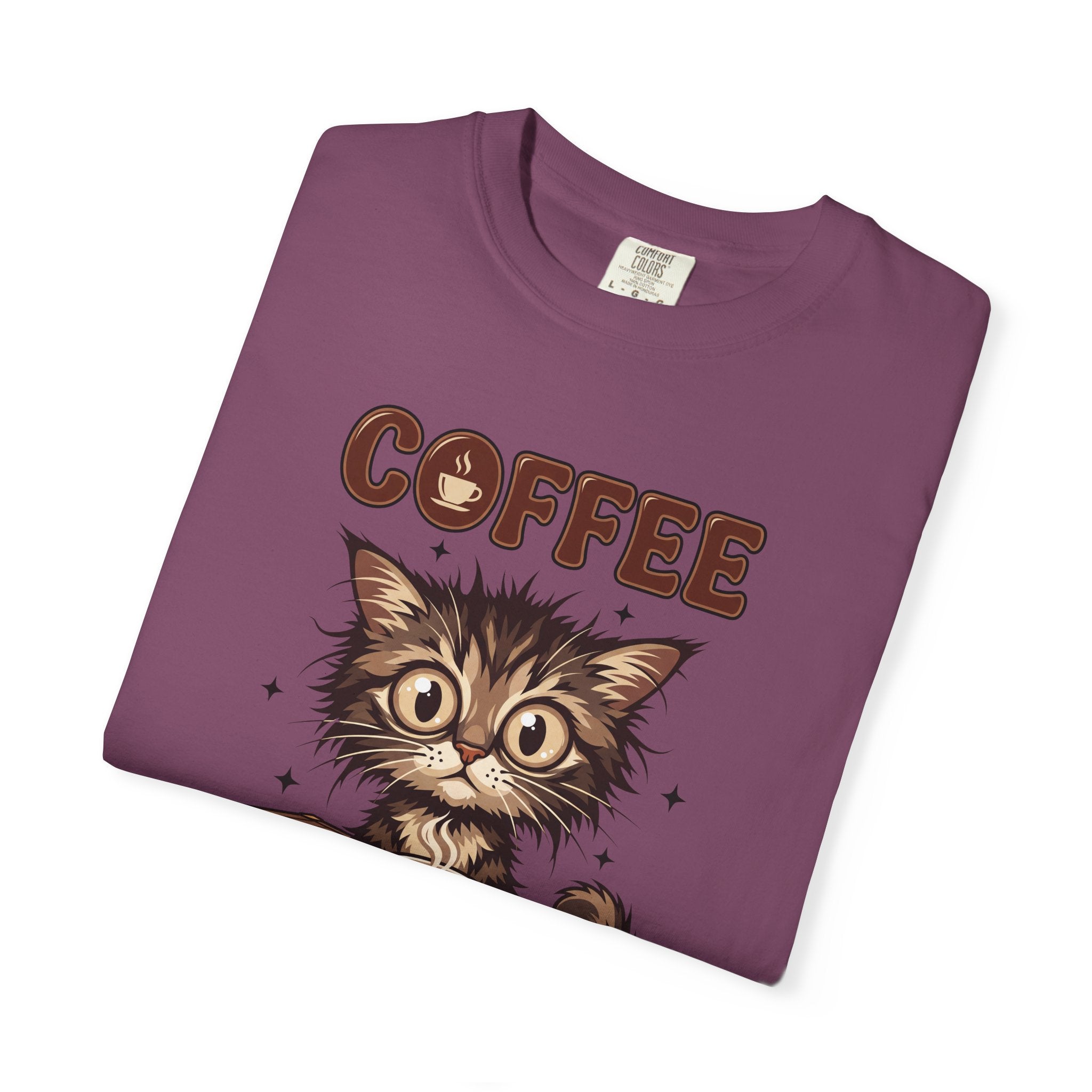 A folded purple unisex cotton t-shirt featuring a graphic of a fluffy kitten and the word COFFEE.