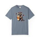 Blue-grey Comfort Colors unisex t-shirt featuring a raccoon holding a coffee cup with a skull logo.