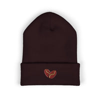 A dark brown cuffed beanie with an embroidered coffee bean heart on the cuff.