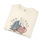 Cream-colored unisex t-shirt featuring a graphic of a duck in a robe drinking from a coffee mug.