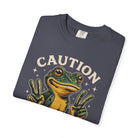 Dark grey t-shirt featuring a graphic of a frog making peace signs with the word CAUTION above it.