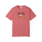 A pink t-shirt featuring a stick figure with a coffee mug and a dog, with the text Coffee and Dogs.