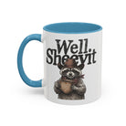 A white ceramic mug with a blue handle and rim, featuring a raccoon in a cowboy hat holding a mug.
