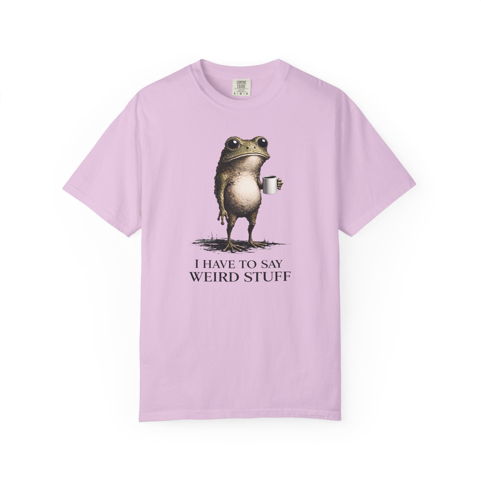 A light pink cotton t-shirt featuring a graphic of a frog holding a coffee mug with text below.