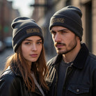 Two people wear dark gray cuffed beanies with "COFFEE" spelled out in periodic table elements.