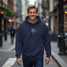 A man wearing a navy blue Perk Up Plot On hoodie with a coffee cup graphic on a city street.