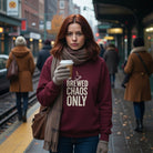 A person wearing a black crewneck sweatshirt with the text Brewed Chaos Only printed on the chest.