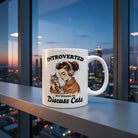 White ceramic mug with a woman holding a cat and the text Introverted But Willing To Discuss Cats.