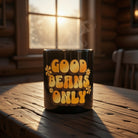Black ceramic mug with retro orange Good Beans Only text and flowers on a rustic wooden table.