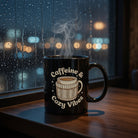 Black ceramic mug with Caffeine and Cozy Vibes text and a sweater-wrapped cup illustration.