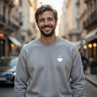 A man wears a gray crewneck sweatshirt featuring a small white steaming coffee cup graphic.
