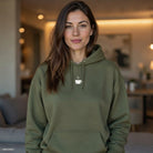 A woman wears an olive green hoodie featuring a small white coffee cup icon on the chest.